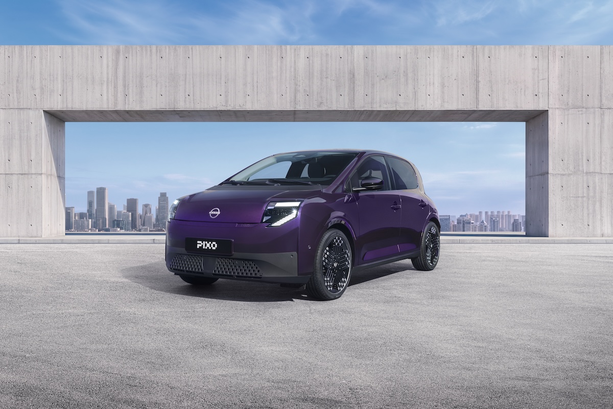Nissan PixoNissan PIXO electric city car parked beneath a modern concrete structure, with a city skyline in the background.